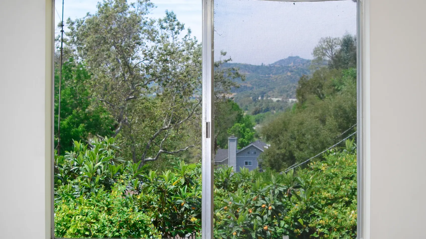 Blick durch ein Fenster auf Berge und Garten — Rollladen schließt beim Scrollen