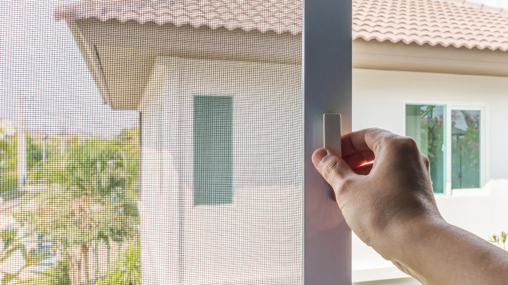 Hand öffnet einen Insektenschutz-Spannrahmen am Fenster — Fliegengitter Graz